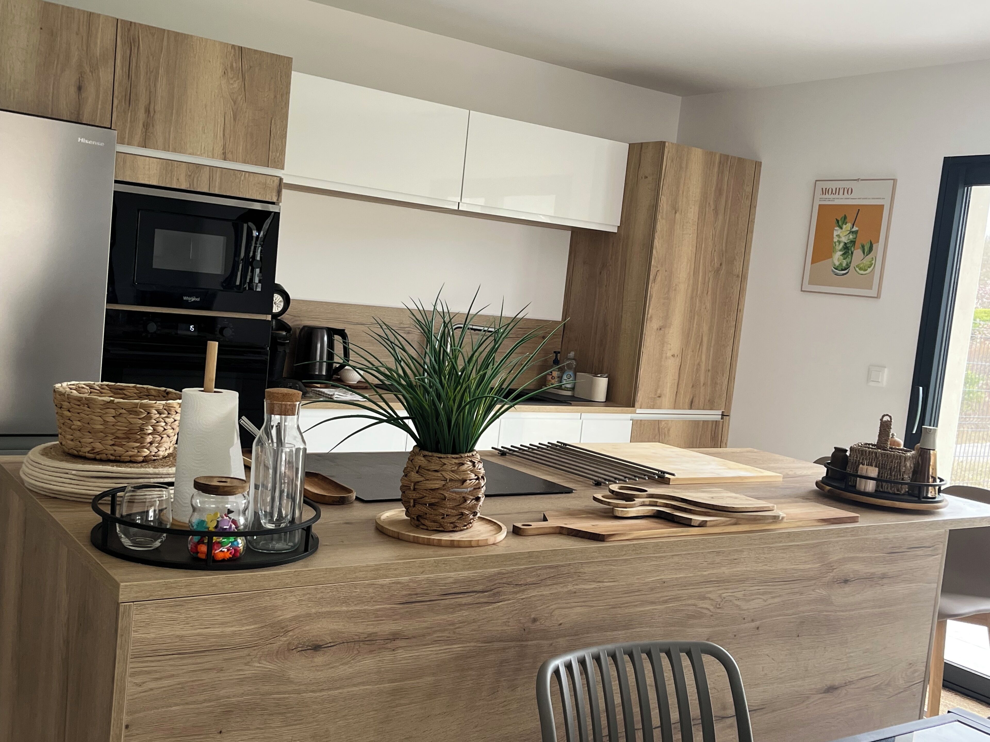 A modern kitchen with wooden cabinets, a microwave, a coffee maker, and a potted plant.