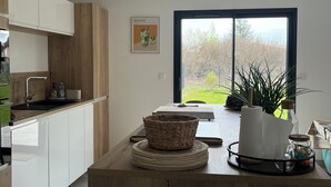 A modern kitchen with white cabinets, a wooden countertop, a large window, and a framed picture on the wall. - La Lézardière House with swimming pool in Ruoms, close to nature and rivers (Ruoms)