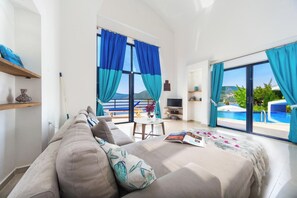 Une chambre d’hôtel moderne dotée d’un grand lit, d’un coin repas, d’une télévision et offrant une vue sur une piscine.