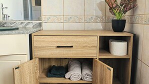 A bathroom with a wooden vanity, a glass shelf, a potted plant, and a tiled wall. - Cosy T2 in downtown Le Mans, 15 minutes from the 24h circuit (Le Mans)