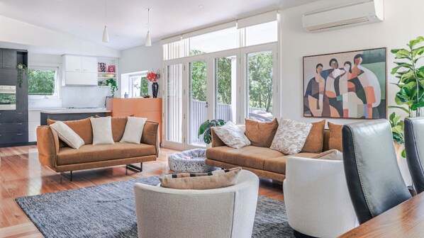 A modern living room with two sofas, a coffee table, and a dining area with a kitchen in the background.