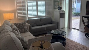 Una sala de estar con un sofá, una mesa de centro, una lámpara y un televisor.