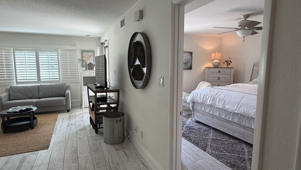 Una sala de estar moderna con sofá, mesa de centro, mueble para televisión y una pieza decorativa en la pared.