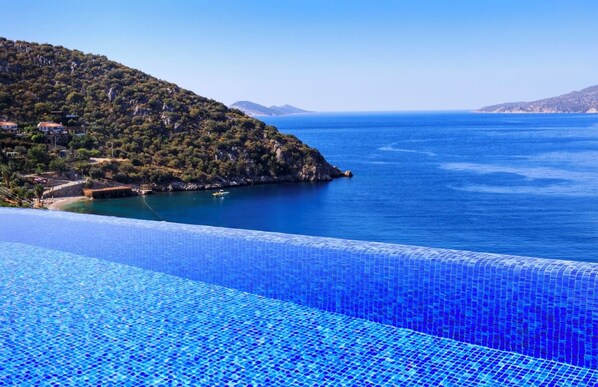 A coastal view with a clear blue sea, a hilly landscape, and a tiled infinity pool. - The White Collection - Villa Sky (Kaş/Antalya)