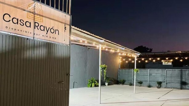 Ein verschlossener Eingangsbereich mit einem Schild für 'Casa Rayón' und einem überdachten Außenbereich mit Lichterketten.