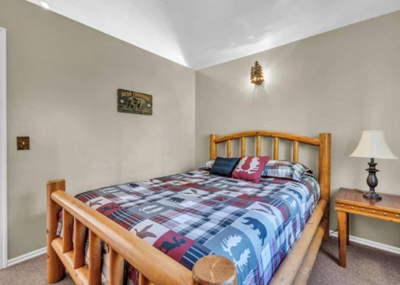 Ein Schlafzimmer mit einem hölzernen Bettgestell, einer Steude mit Tiermotiven, einer Nachttischlampe und einer Wandleuchte.