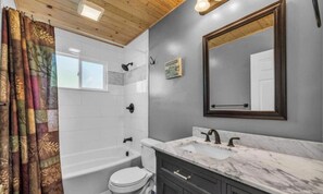 Une salle de bain avec une baignoire, des toilettes, un meuble-lavabo et un grand miroir.
