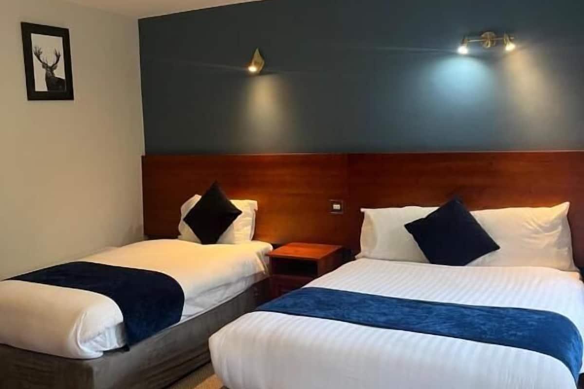 A hotel room with two beds, a wooden headboard, a framed picture on the wall, and a ceiling light fixture.