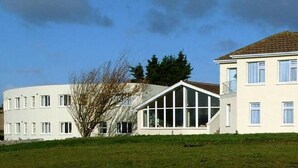 A two-story building with a flat roof, large windows, and a visible staircase leading to the entrance. - Fernhill Lodge Carrigaline (Carrigaline)