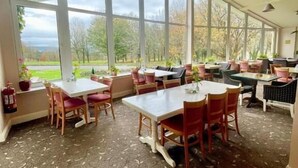 A spacious dining area with large windows, a fire extinguisher, and a patterned floor. - Fernhill Lodge Carrigaline (Carrigaline)