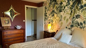Camera da letto con letto, comò, specchio e carta da parati a motivi floreali.