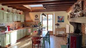 Una cucina con travi in legno, un'area pranzo con sedie, un fornello e una finestra.