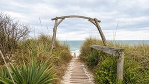 A wooden pathway leading to a beach with a wooden archway. - Beachfront Escape | Walk to Trading Post | 4BR (Port St. Joe)