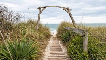 Ein Holzweg, der zu einem Strand mit einem hölzernen Bogen führt.