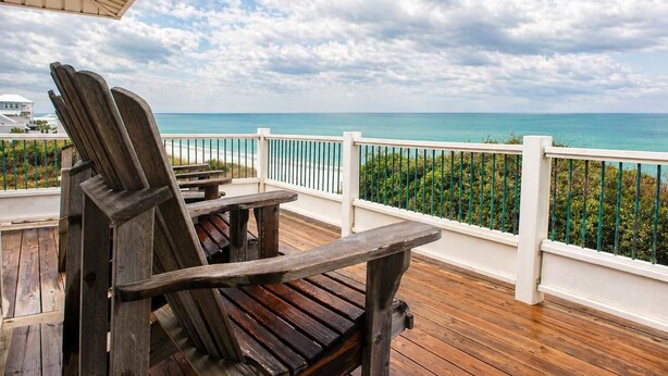 A wooden deck with a view of the ocean and a white railing. - Beachfront Escape | Walk to Trading Post | 4BR (Port St. Joe)