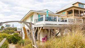 A beachfront house with a wooden deck, a staircase, and a view of the ocean. - Beachfront Escape | Walk to Trading Post | 4BR (Port St. Joe)
