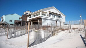A coastal house with a balcony, a wooden fence, and a clear blue sky. - Rehab- Beach front, Sleeps 9 (Port St. Joe)