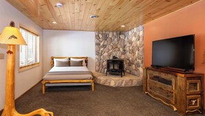 A bedroom with a bed, a television, and a stone wall. - 5BR Family-Friendly Home Near Horse Show w/ RV (Williamsburg)