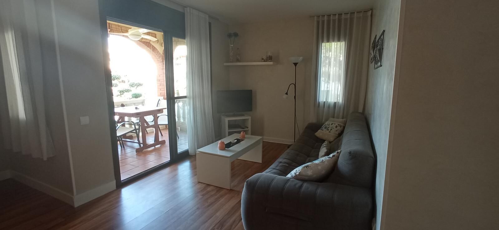 A living room with a sofa, a coffee table, a TV, and a dining area with chairs and a table.