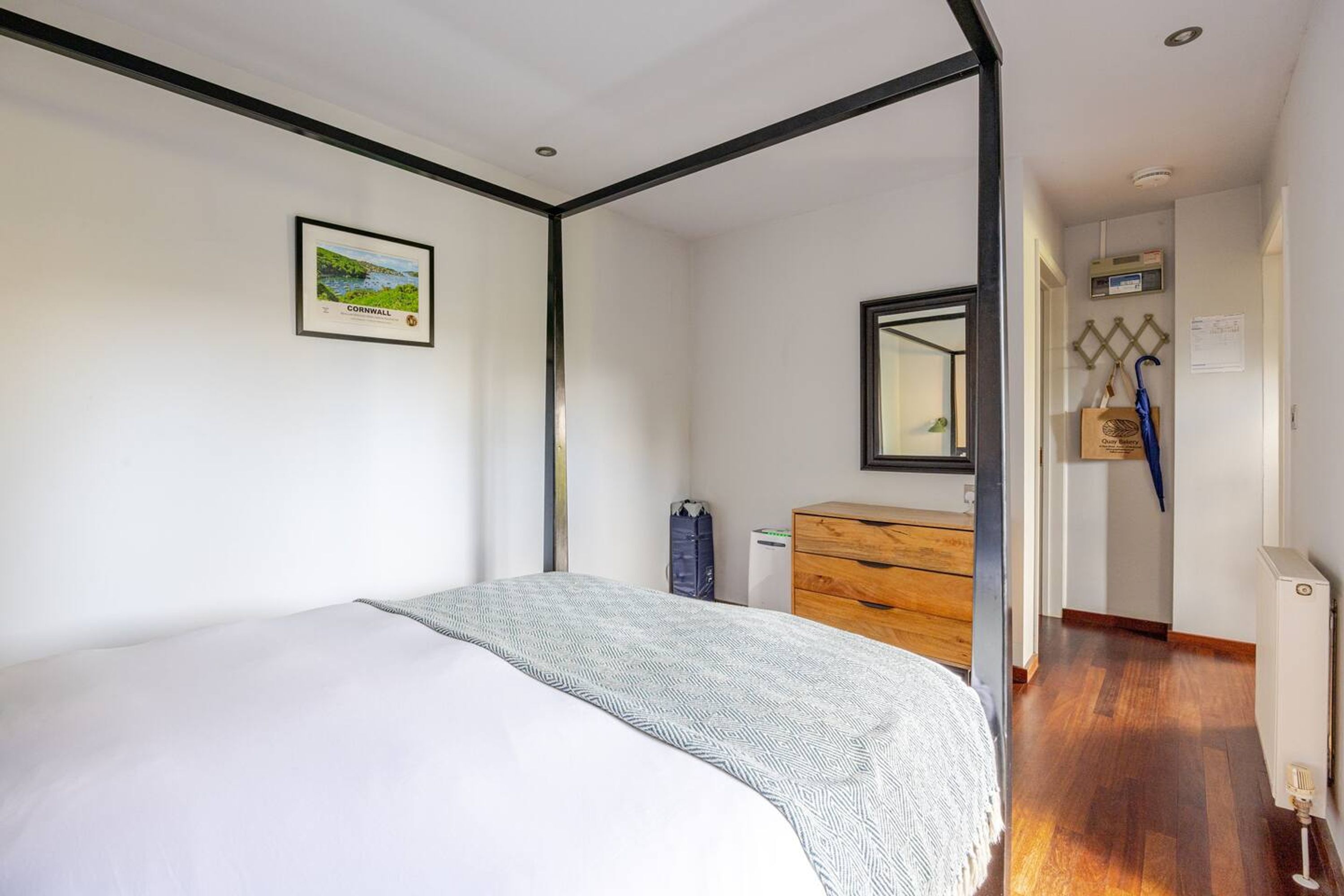 A bedroom with a bed, a dresser, a mirror, and a framed picture on the wall.