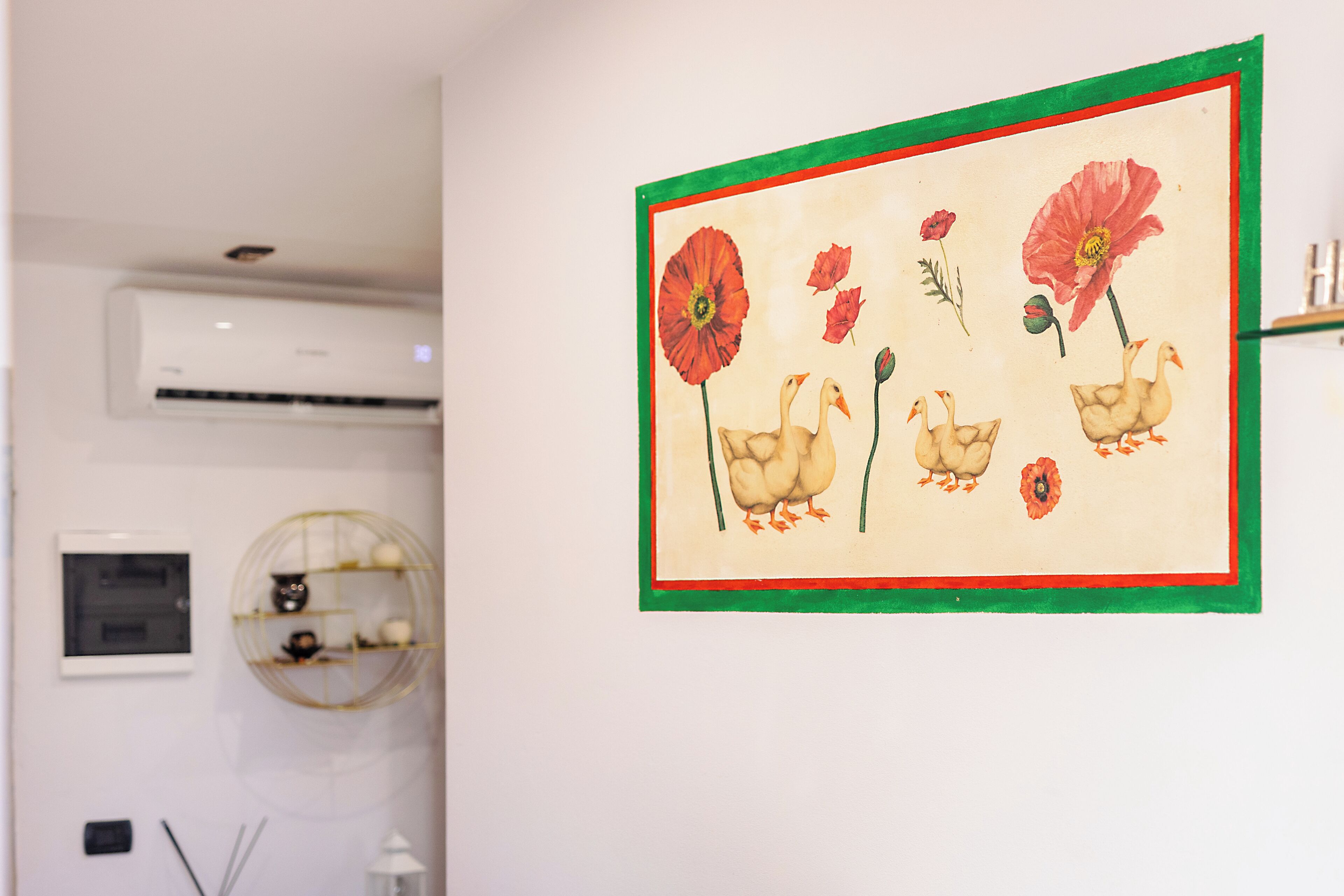 A wall with a framed artwork of birds and flowers.