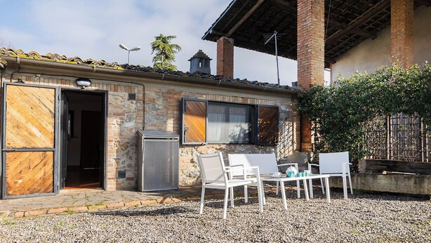 A building with a stone facade, a door, a window, and a patio area with chairs and a table.