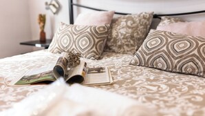 A neatly made bed with patterned pillows and a magazine on it.