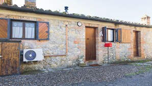A stone building with a wooden door, a window with curtains, and a red mailbox.