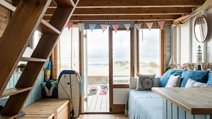 Un interno in legno con un letto, un tavolo e vista sulla spiaggia.