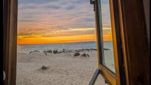 Una finestra con vista su una spiaggia al tramonto.