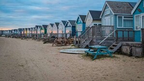 Una fila di case sulla spiaggia con terrazze in legno e scale che scendono verso la spiaggia.