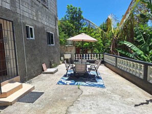 Eine Terrasse mit Tisch, Stühlen und einem kleinen Sonnenschirm, mit einem Betonboden.