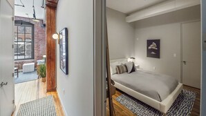 A bedroom with a bed, a window, and a door leading to a balcony.