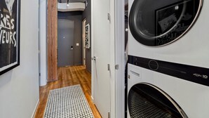 A laundry room with a washing machine and dryer, wooden flooring, and a patterned rug.