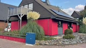 A red building with a sloped roof, solar panels, and a satellite dish.