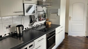 A modern kitchen with stainless steel appliances, a microwave, and a stove. There are white cabinets and a black countertop.