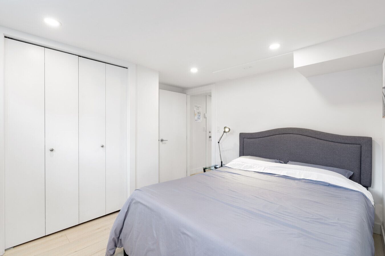 Un dormitorio con cama, armario y lámpara de escritorio.
