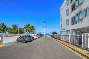A street with parked cars, a white building with green shutters, and a clear blue sky. - Cocomar Beach Escape,  Steps from the Ocean, Perfect for 2 (Carolina)