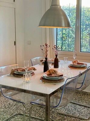 Un tavolo da pranzo con sedie trasparenti in vetro, un piano in vetro e una lampada a sospensione.