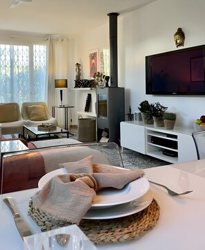 Una sala de estar moderna con un sofá, un televisor de pantalla plana, una chimenea y elementos decorativos.
