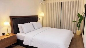A hotel room with a bed, bedside lamps, a potted plant, and a window with curtains. - Cosy & Chic Apartment with Secure Parking in the Heart of Casablanca (Dar-el-Beida)