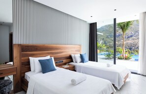 A modern hotel room with two beds, a wooden headboard, a large window with a view of a pool and mountains, and a nightstand with a lamp. - Villa Sade: A Modern Luxury Retreat with Infinity Pool and Sweeping Views (Kaş/Antalya)