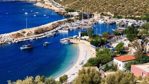 A coastal town with a marina, sandy beach, and residential buildings. - Villa Sade: A Modern Luxury Retreat with Infinity Pool and Sweeping Views (Kaş/Antalya)