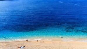 A beach with clear blue water, a sandy shore, and a distant island. - Villa Sade: A Modern Luxury Retreat with Infinity Pool and Sweeping Views (Kaş/Antalya)