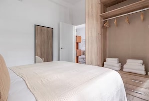 A bedroom with a bed, a wooden wardrobe, and a door. - Spectacular Apartment in Salamanca district (Madrid)