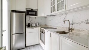 Una cocina moderna con electrodomésticos de acero inoxidable, encimera de mármol y horno empotrado.