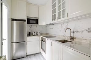 A modern kitchen with stainless steel appliances, a marble countertop, and a built-in oven. - Spectacular Apartment in Salamanca district (Madrid)