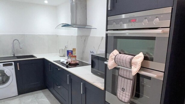 A modern kitchen with a built-in oven, a microwave, and a washing machine. - Central 1 Bed Apartment - Sleeps 2 With Wifi (Wellingborough)