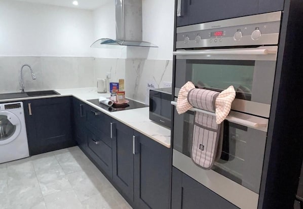 A modern kitchen with a built-in oven, a microwave, and a washing machine.