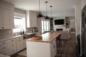 Een moderne keuken met witte kasten, een houten eiland, hanglampen en een inbouwoven.